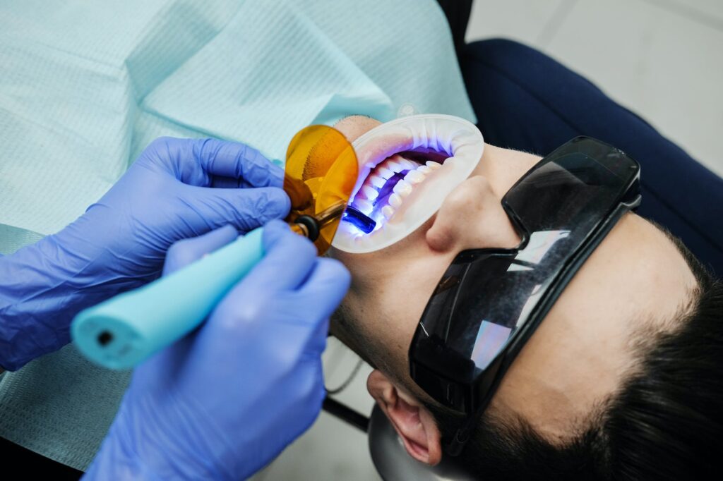dentist making oral examine of patient with uv light equipment