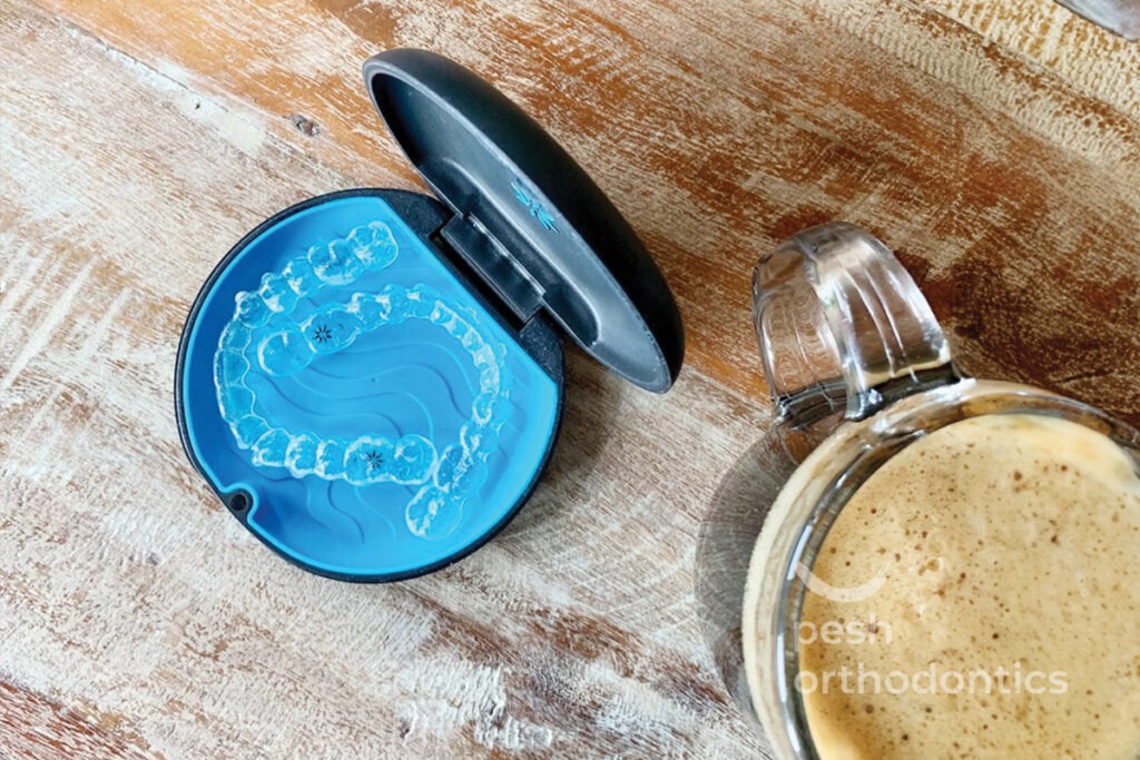 Close-up image of an Invisalign container with a clear aligner placed beside it, highlighting the transparent and discreet design of the aligner for teeth straightening.