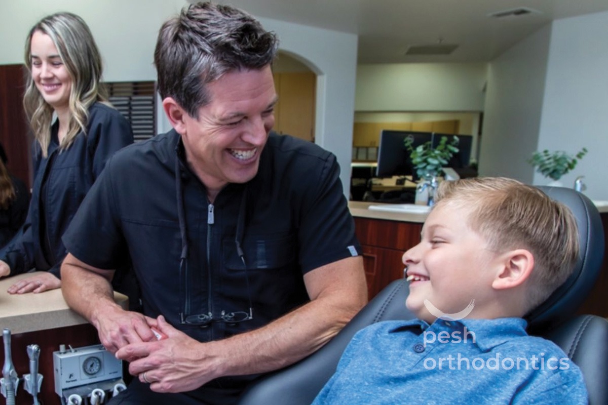 Dr. Pesh and a young patient smiling at each other during the patient's first orthodontic visit at Pesh Orthodontics.