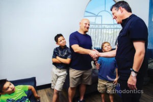 Dr. Pesh shakes a father’s hand while his three sons look on during a visit to Pesh Orthodontics in Murrieta, California.